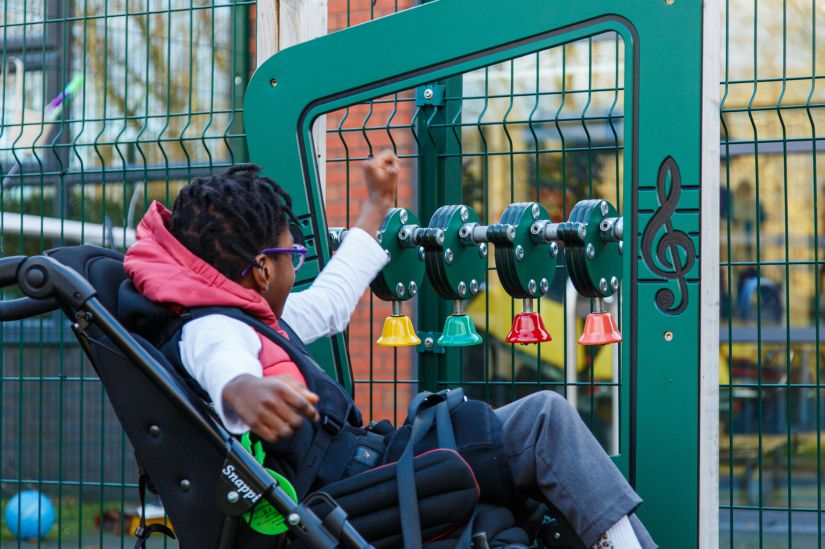 This image shows a female student who is wheelchair bound playing with bells 