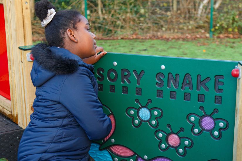 This image shows a female pupil playing with a sensory snake playboard 