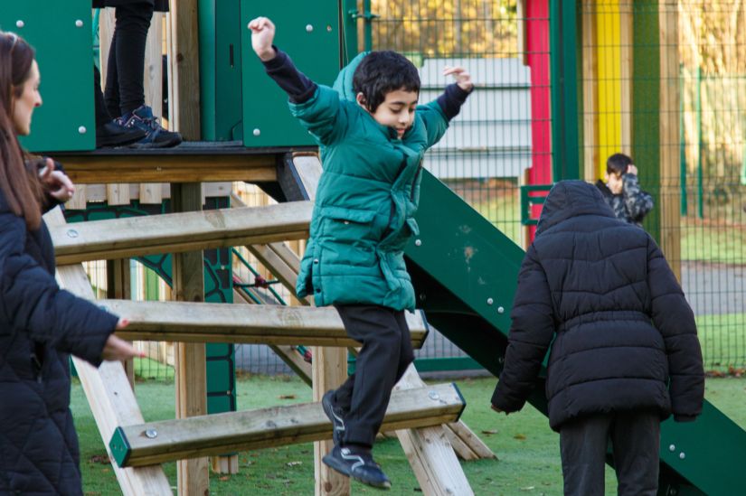 This image shows a male pupil jumping from a playground ladder 