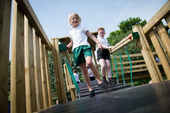 This image shows two children in pe kits running across a playground bridge 