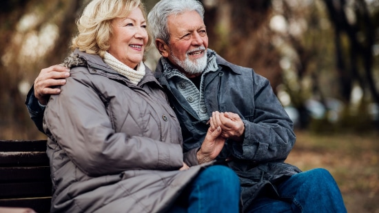 Older couple holding hands while sitting down in the park