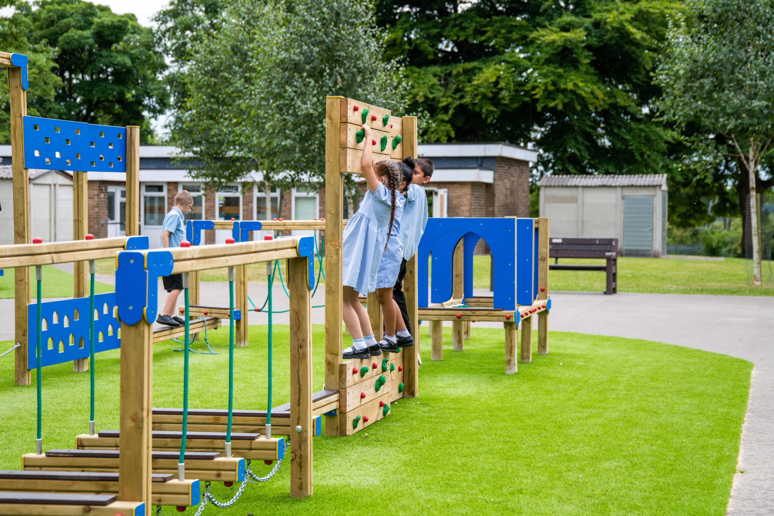 Girls in uniform using the climbing wall on a trim trail