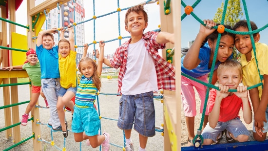 Kids posing for a photo on an outdoor play area climbing net