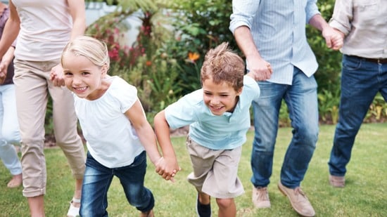 Kids holding hands with their parents running out on the grass