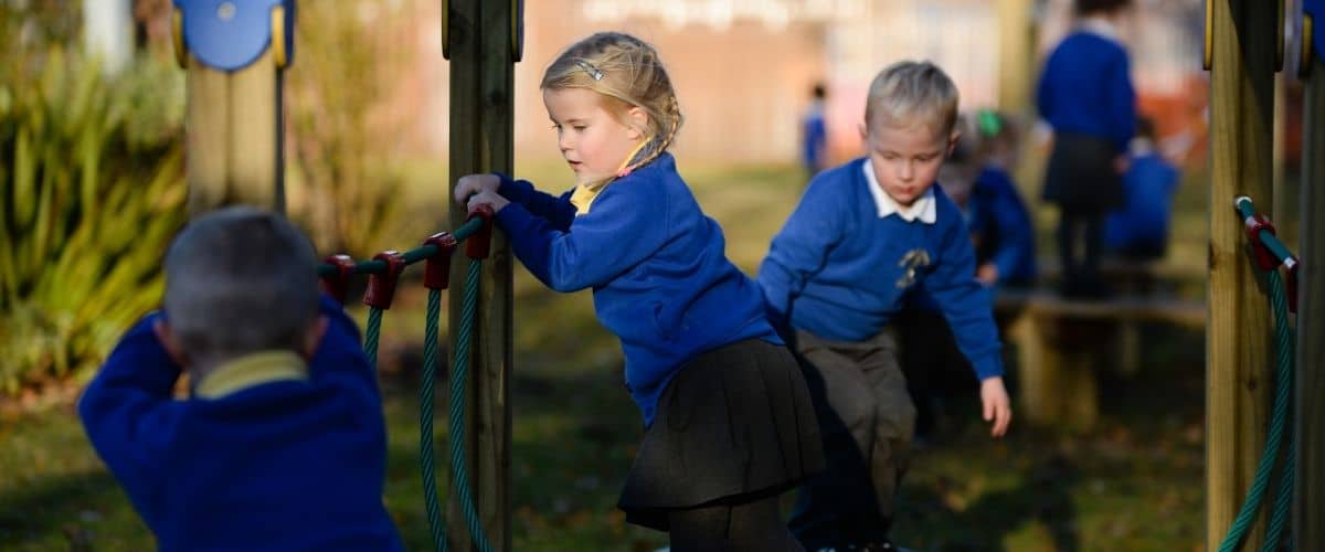 This image shows primary school children climbing on playground equipment.
