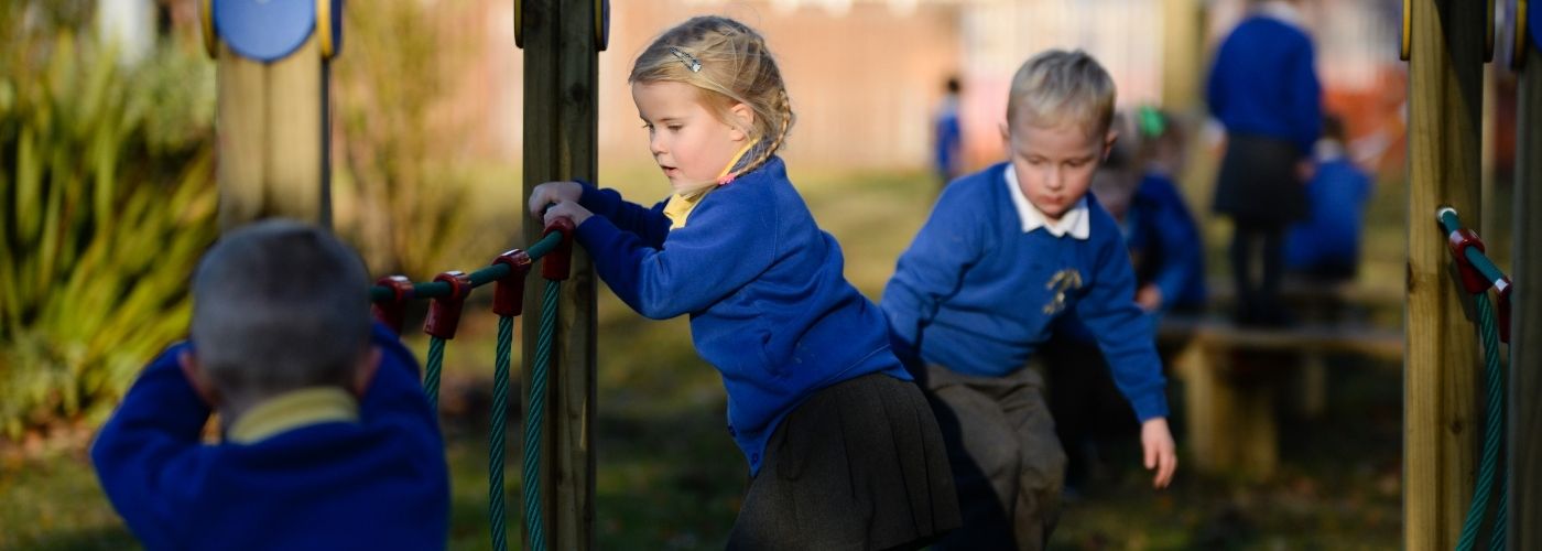 This image shows primary school pupils playing on a rope bridge playground equipment