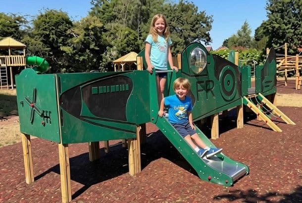 Spitfire shaped outdoor play equipment enjoyed by a boy and girl