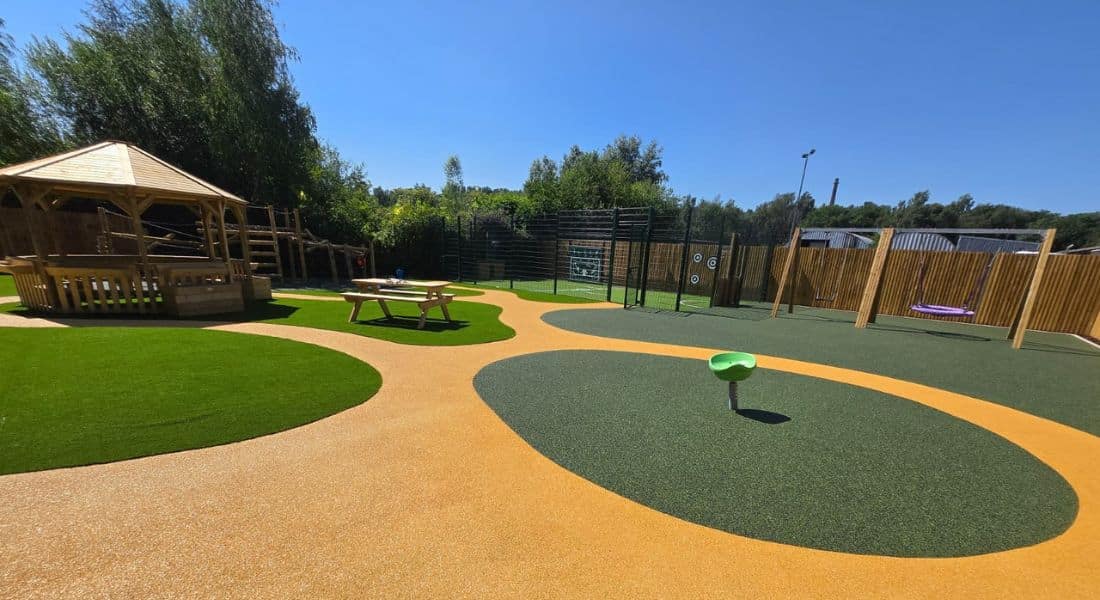 This image shows a Octavia shelter, picnic bench and a combi jungle climber on both wetpour safety surfacing and artificial grass safety surfacing 