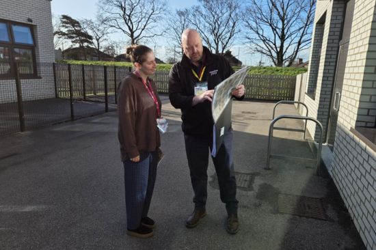 New Website Imagery - Represent Tim This image shows a male sales man showing a female teacher a presenter folder of playground products
