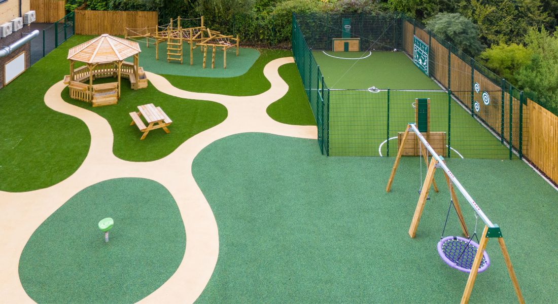 This image shows a Octavia shelter, picnic bench and a combi jungle climber on both wetpour safety surfacing and artificial grass safety surfacing 