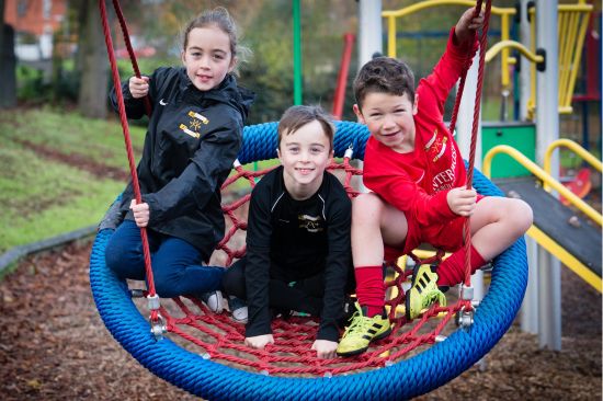 This image shows three children swinging in a basket swing