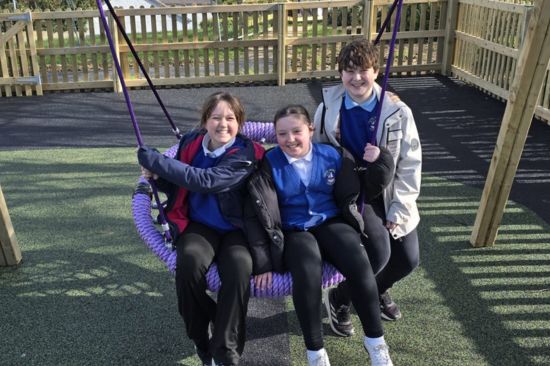 This image shows three children sitting in a basket swing 