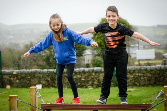 This image shows two children on a wooden beam