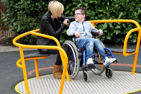 This image shows  a young boy in a wheelchair with his mother 