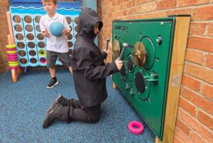 This image shows a young boy playing with a drum playboard