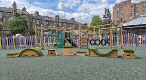 This image shows ABC blocks with a dart activity centre in the background on green wetpour safety surfacing